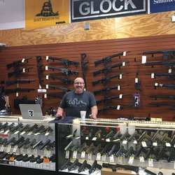 Cap City Outfitters - Chris at the Wall of Freedom with our selection of AR-15s and pistols suitable for concealed carry.