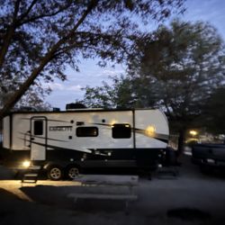 Large campsite with mature trees, picnic table, and full hookups.