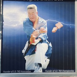 Pan Am Tae Kwon Do Academy - Photo on window of Grandmaster Kim breaking bricks with one hand while holding the bricks with the other hand (speed break).