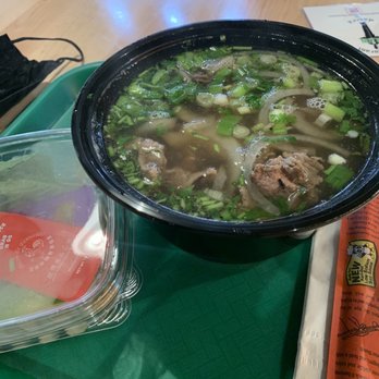 Lan Viet - Hanoi Style Flash Fried Steak Pho (it was a special) - A bowl of Vietnamese beef pho with broth, sliced onions, and chopped green onions on a green tray at a restaurant. - Vietnamese Near Me - Dublin, Ohio