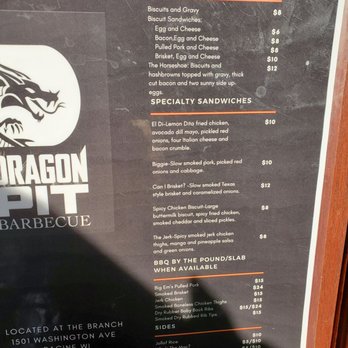 Dragon Pit BBQ - menu - The menu board from Dragon Pit Barbecue features sections for breakfast, specialty sandwiches, BBQ options, and sides. Breakfast includes biscuits with gravy and various egg sandwiches, with prices ranging from $6 to $12. Specialty sandwiches include fried chicken, smoked pork, and brisket, priced between $8 and $12. BBQ options such as pulled pork and brisket are listed with prices from $15 to $24. Sides include rice, mac and cheese, hush puppies, cole slaw, and lemon Dita fries, each priced at $5 or $10. The restaurant is located at 1501 Washington Ave, Racine WI, and operates from 7 am to 6 pm, Tuesday through Friday. - Barbeque Near Me - Racine, Wisconsin