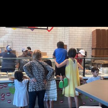 MOD Pizza - Kid hanging over the food that is going on the pizza - Pizza Near Me - Bellaire, Texas