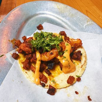 Pilsen Yards - Shrimp taco - A shrimp taco with sauce, chopped herbs, and crispy toppings served on a paper-lined metal tray at Pilsen Yards in Chicago. - Tacos Near Me - Chicago, Illinois