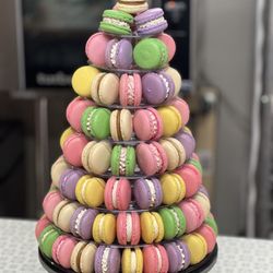Aba Macarons - This colorful macaron tower showcases a blend of pastel pink, green, and aqua macarons arranged on a tiered stand. Perfect for dessert table