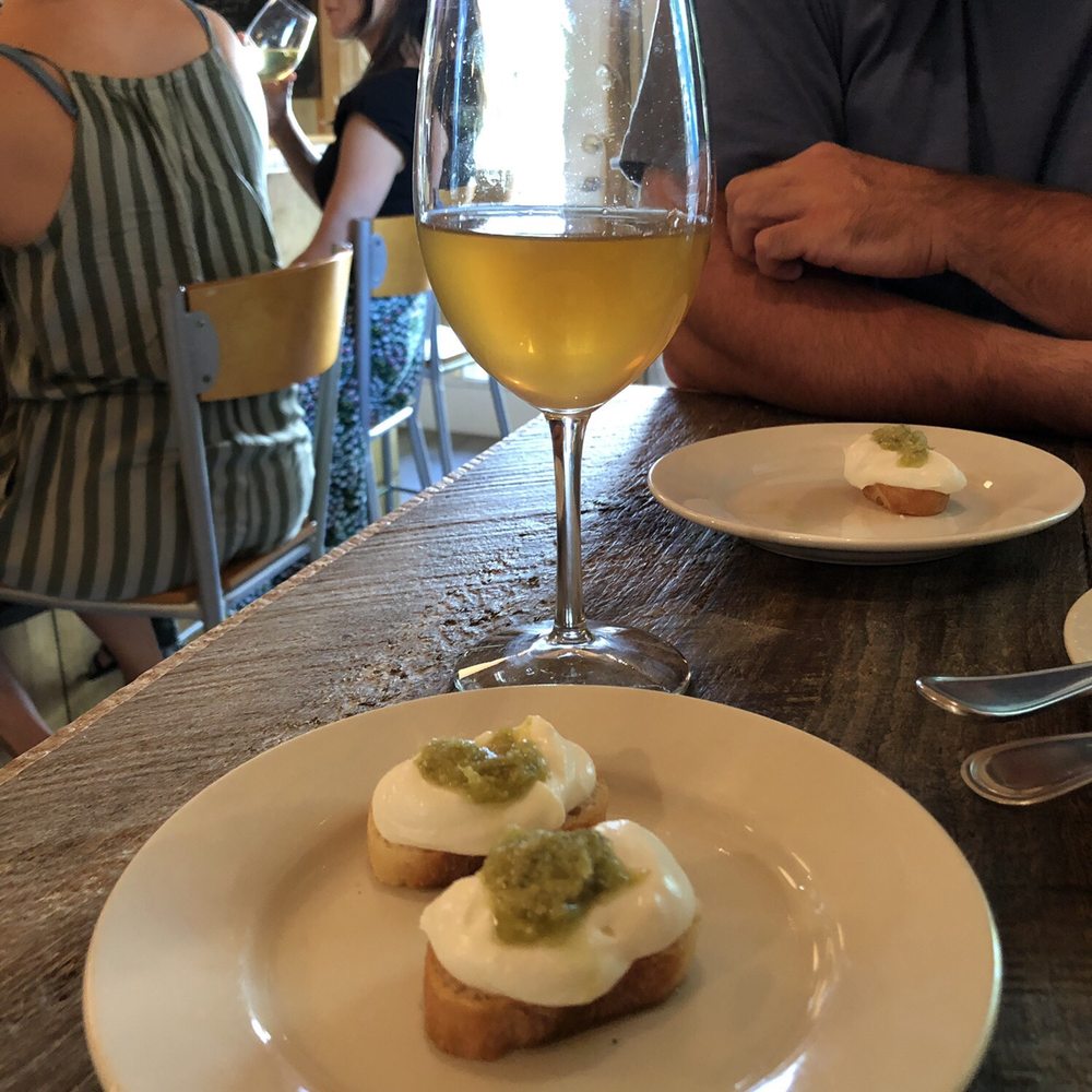 Callicoon Wine Merchant - House made ricotta, with garlic scape pesto with a glass of Modus Bibendi Orange Wine 2018 Elios - Wine Bars Near Me - Callicoon, New York Callicoon Wine Merchant - House made ricotta, with garlic scape pesto with a glass of Modus Bibendi Orange Wine 2018 Elios - Wine Bars Near Me - Callicoon, New York