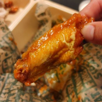 Wingstop - a hand holding a piece of food - Chicken Wings Near Me - Fullerton, California