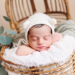 Cami Heart Photography - Sleeping newborn baby in a vintage wicker chair with soft neutral fabrics and greenery. Orange County newborn photography.