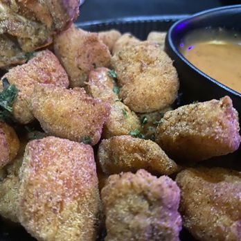 TNT Restaurant - Seafood bites - Fried seafood bites garnished with herbs are served with a dipping sauce in a black bowl, likely at a restaurant. - American Near Me - Chicago, Illinois