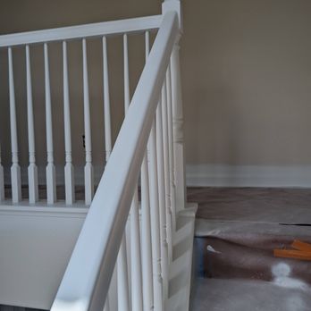 HB Kitchen Bath - The painting crew is very detail oriented. Not a paint drop on the existing floor! - The image features a white staircase railing with a newel post and vertical spindles, situated in a room with beige walls. The floor is covered with protective material, indicating ongoing renovation or construction work. The railing is clean and freshly painted, with no visible damage or wear. - Kitchen & Bath Near Me - Hayward, California