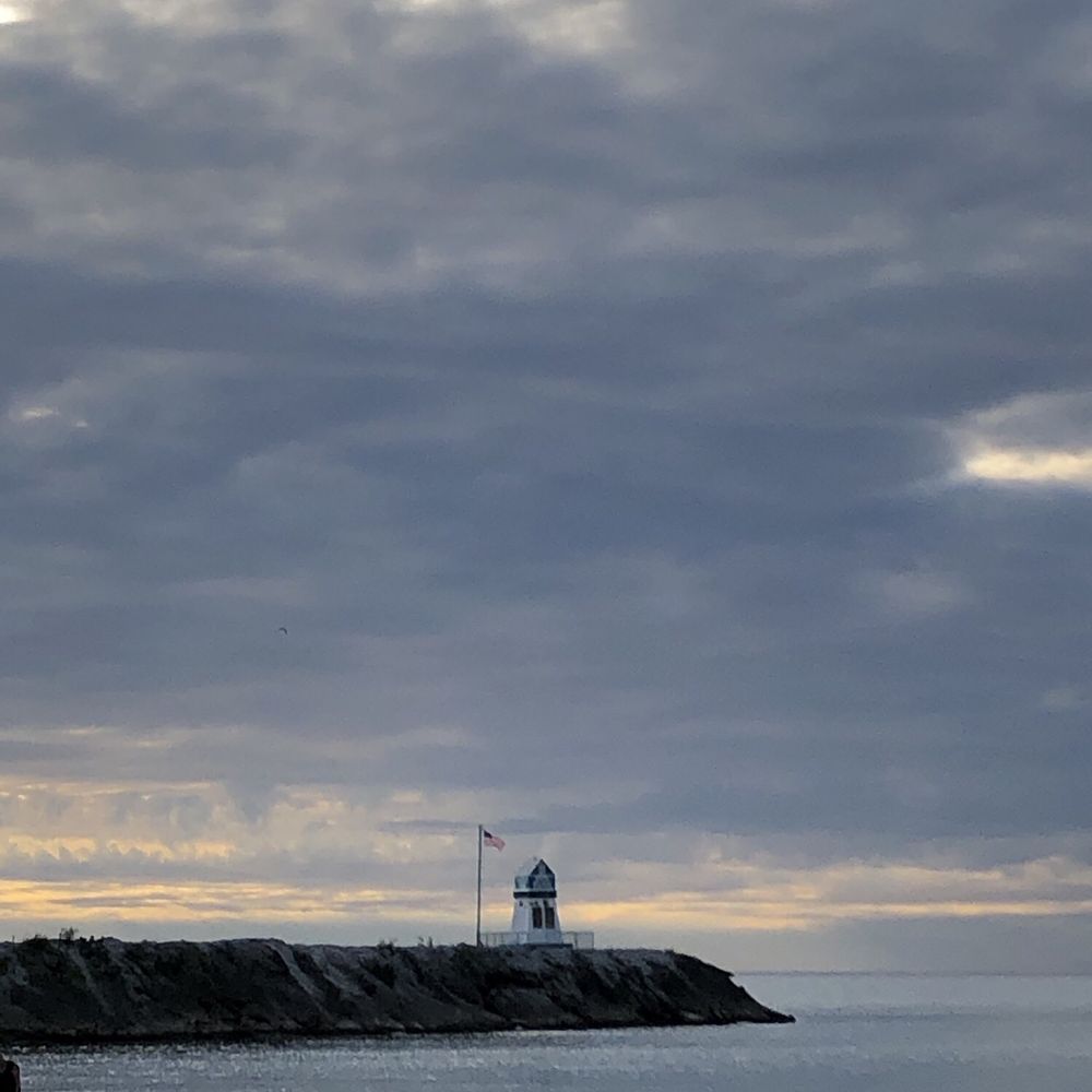 Snack Shack - a person standing on a rocky beach with a lighthouse in the background - Salad Near Me - Lorain, Ohio Snack Shack - a person standing on a rocky beach with a lighthouse in the background - Salad Near Me - Lorain, Ohio