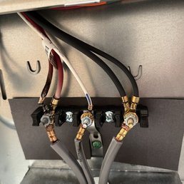 Here is the photo that was taken, the wire on the left is singed off and cost the mother board to malfunction. - The image shows electrical wires connected to terminals inside an appliance or electrical panel, with some wires stripped and secured with connectors.