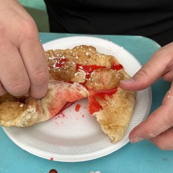 Frybread Hut - a person taking a bite out of a piece of pizza - Food Stands Near Me - Supai, Arizona