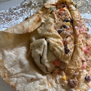 QDOBA Mexican Eats - This is what they did instead of just remaking the burrito. What a joke - A partially eaten burrito with a soft flour tortilla, revealing fillings like vegetables, meat, and cheese. The burrito is placed on crumpled aluminum foil on a white surface, with some fillings visible and the tortilla folded around the ingredients. - Mexican Near Me - Mansfield, Massachusetts