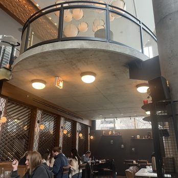 River North Bistro - A restaurant interior features a mezzanine with a glass railing, ceiling lights, and a dining area with patrons seated at tables. - American Near Me - Chicago, Illinois