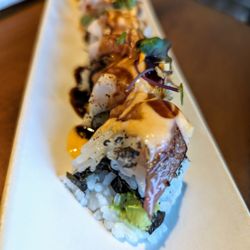 Sushi Suyu - Hamachi Fever roll. $16. Inside: shrimp tempura, avocado. Top: Seared yellowtail, microgreens, garlic chips, Sriracha aioli, sweet soy.