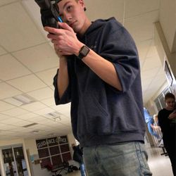 A teen taking aim in a lit school hallway. Mobile laser tag works indoors with the lights on, so schools can host it almost anywhere.