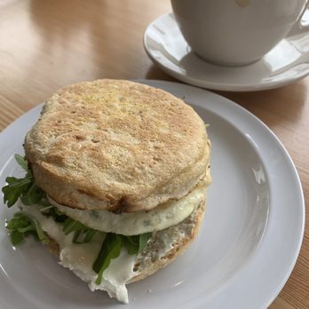 Vinal Bakery - Front: GOAT sandwich on oat sesame English muffin. Medium fried egg, spicy pesto, goat cheese pesto, arugula. Back: Latte - Cafes Near Me - Somerville, Massachusetts
