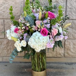Lush vase arrangement with hydrangea, roses, lilies, stock, and eucalyptus in soft pink, white, and green tones for an elegant garden look.
