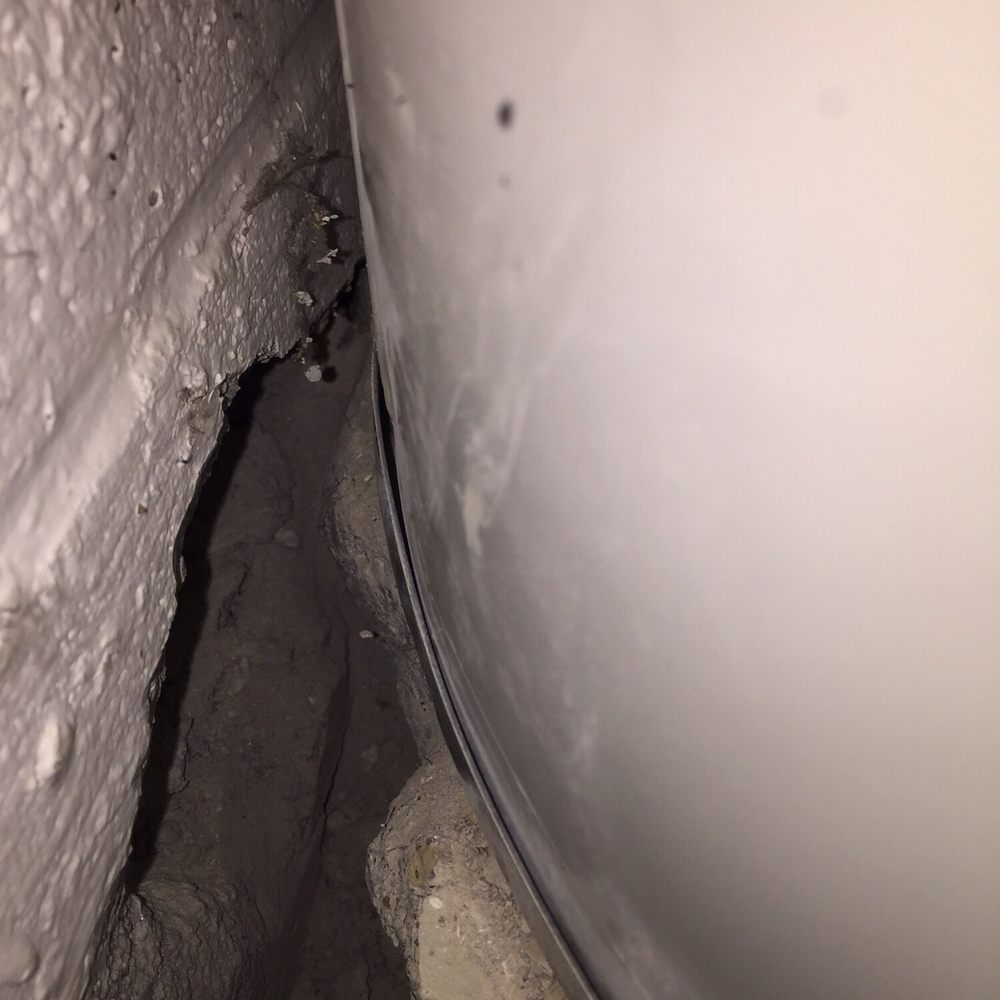 Pioneer Basement Waterproofing - Damage to block wall behind hot water heater. Created by jack hammering. There was no room for this the tank was flush to the wall. - Waterproofing Near Me - Akron, Ohio Pioneer Basement Waterproofing - Damage to block wall behind hot water heater. Created by jack hammering. There was no room for this the tank was flush to the wall. - Waterproofing Near Me - Akron, Ohio
