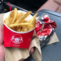 a hand holding a cup of french fries