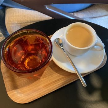 Corvus Coffee Roasters - A glass of tea and a cup of coffee are placed on a wooden tray at Corvus Coffee Roasters in Arvada, CO. - Coffee & Tea Near Me - Arvada, Colorado