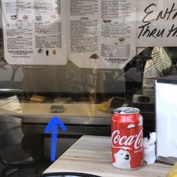 Cell phone sitting on the cutting board where they prepare food / sandwiches