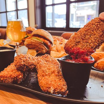 Socibowl - a person dipping a piece of chicken nuggies - Bars Near Me - Muskegon, Michigan Socibowl - a person dipping a piece of chicken nuggies - Bars Near Me - Muskegon, Michigan