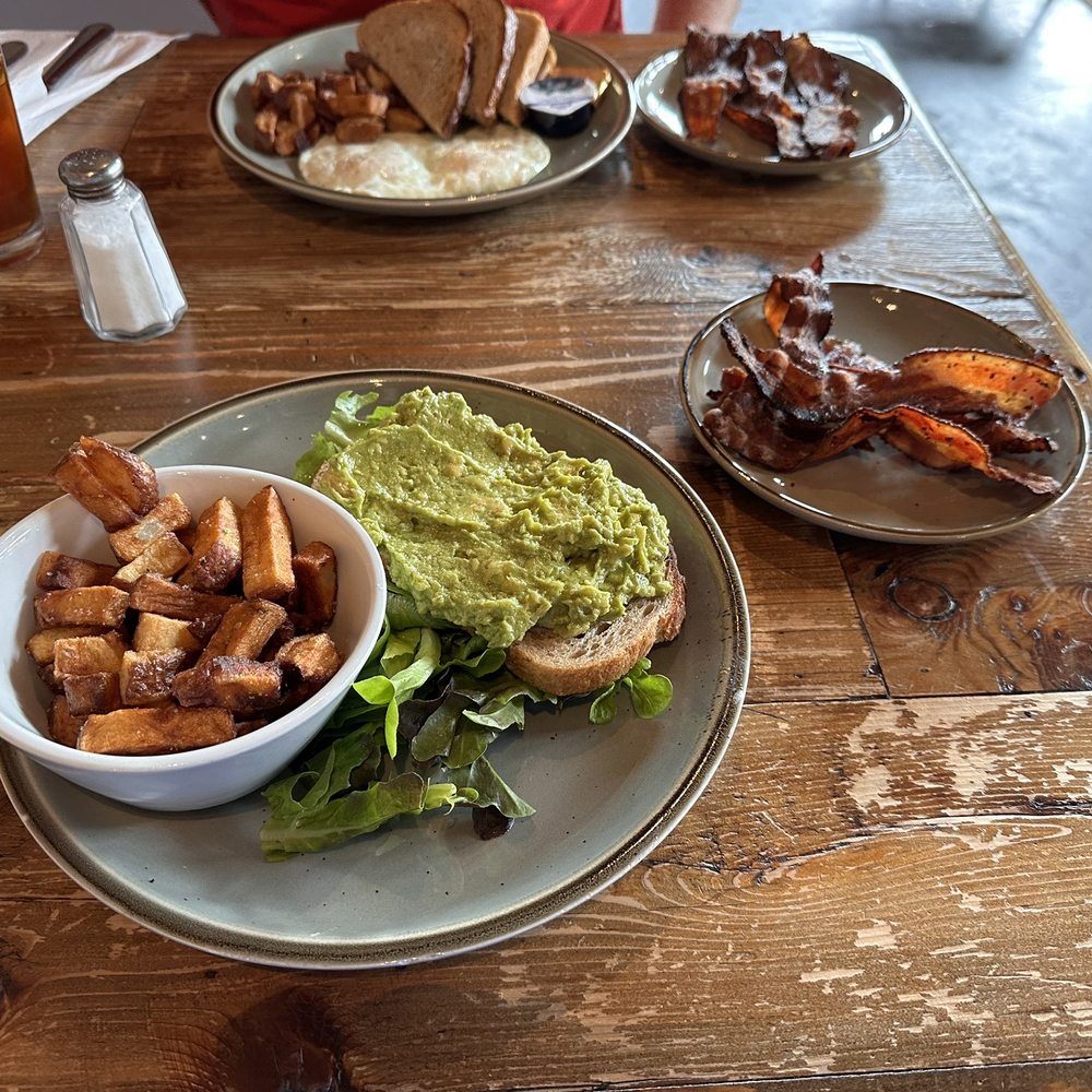 Breakaway Cafe - Avocado toast (substituted with potatoes instead of two eggs), added bacon, and another plate with two over easy eggs, bacon, and toast. - Coffee & Tea Near Me - Chapel Hill, North Carolina