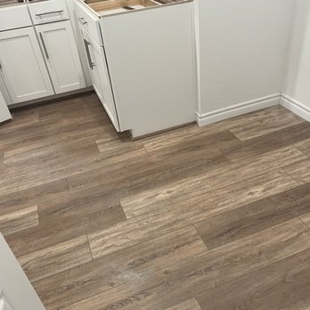 Adriannas Flooring - a kitchen with white cabinets and wood floors - Flooring Near Me