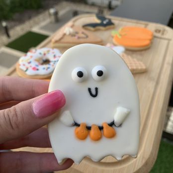 Girls and Aprons - a hand holding a decorated cookie - Desserts Near Me Girls and Aprons - a hand holding a decorated cookie - Desserts Near Me