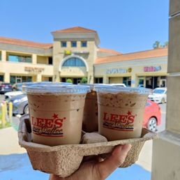 a hand holding two cups of iced coffee