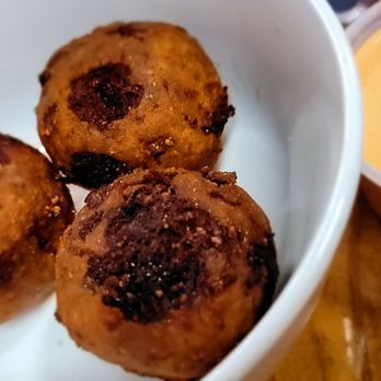 Cormier’s Kitchen - Boudin balls with Cajun ranch- must get these!!! - Three fried food balls with a crispy exterior are in a white bowl, accompanied by a yellow dipping sauce in a small container. - Southern Near Me - Spring, Texas