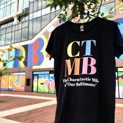 Visit Baltimore - The new (CTMB) brand souvenir T-Shirt in front of the 'Our Baltimore' Mural.