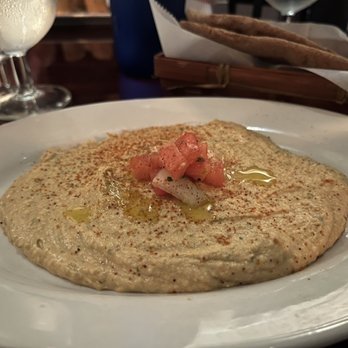 Towne Crier Cafe - Hummus Appetizer - A serving of hummus topped with diced tomatoes, olive oil, and paprika, served on a white plate at a restaurant. - Music Venues Near Me - Beacon, New York