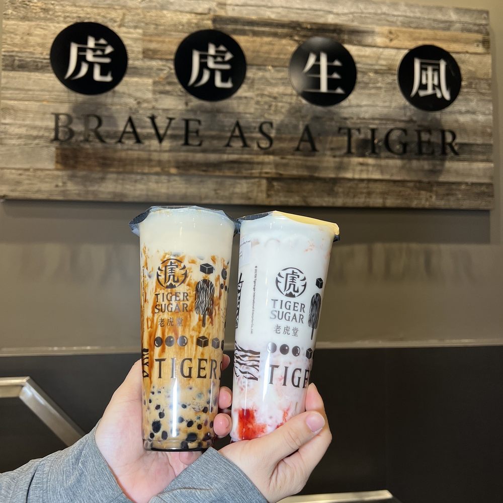 a person holding two cups of bubble tea a person holding two cups of bubble tea