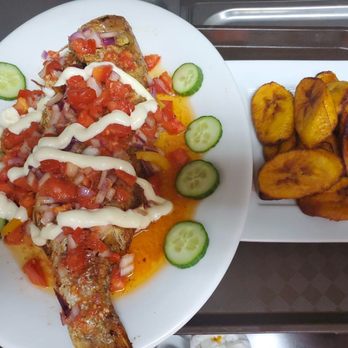 Delish Dining - Whole Tilapia fish well garnished with tomatoes and onion. - African Near Me - Calgary, Alberta