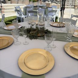 One of the table settings: Gold chargers, champagne flutes, water goblets, cylinder vases, tables and linen One of the table settings: Gold chargers, champagne flutes, water goblets, cylinder vases, tables and linen