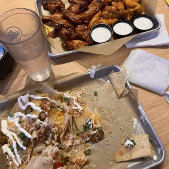Buffalo Wild Wings - Half eaten nachos with chicken and bulleit bourbon bbq wings/spicy garlic wings. - Sports Bars Near Me - Waco, Texas
