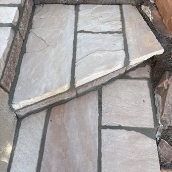 AZR Landscape & Construction - ; and Rehad old dilapidated garden steps with a solid beautiful flagstone upgrade! - A stone pathway features large, irregular flagstones with mortar joints, surrounded by soil and smaller rocks, likely part of outdoor landscaping. - Masonry/Concrete Near Me