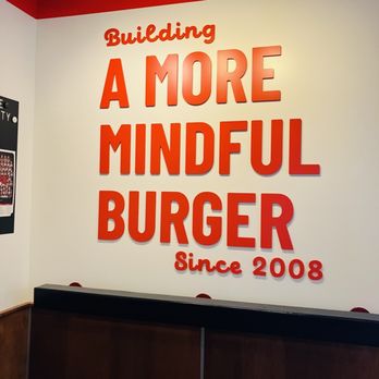 Epic Burger - Their motto - A wall features a large sign with the phrase "Building A More Mindful Burger Since 2008" in bold red letters, with a red and white color scheme. - Burgers Near Me - Barrington, Illinois