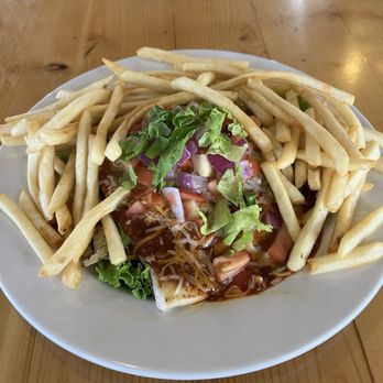 The 377 Brewery - Tortilla Burger - A plate features a taco topped with lettuce, tomatoes, and sauce, surrounded by French fries on a wooden table. - Brewpubs Near Me - Albuquerque, New Mexico
