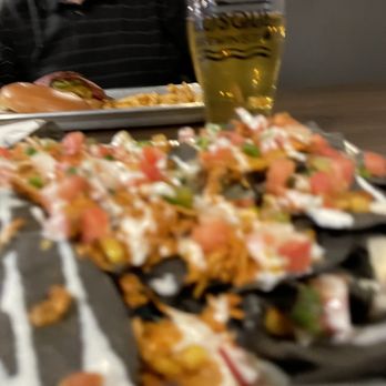 Bosque Brewing Co - Heights Public House - Blurry chicken nachos and cider with cheeseburger and fries in the distance. - Breweries Near Me - Albuquerque, New Mexico Bosque Brewing Co - Heights Public House - Blurry chicken nachos and cider with cheeseburger and fries in the distance. - Breweries Near Me - Albuquerque, New Mexico