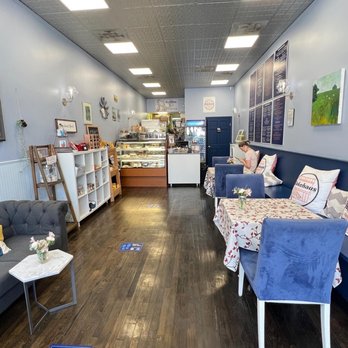 Bakehaus - Interior overlook - A bakery interior with blue walls, seating areas with cushions, and a display case of baked goods at the back. - Desserts Near Me - Belmont, Massachusetts