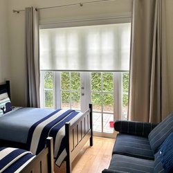Budget Blinds of Indian River County - These roller shades offer flexible light control, while the drapes add softness, texture, and a finished look to this local bedroom.