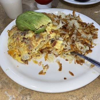 Raspberry's Pancake House - A strange looking bacado. - A breakfast plate featuring scrambled eggs, crispy hash browns, and half an avocado, served on a white plate at a restaurant. - Breakfast & Brunch Near Me - Steger, Illinois
