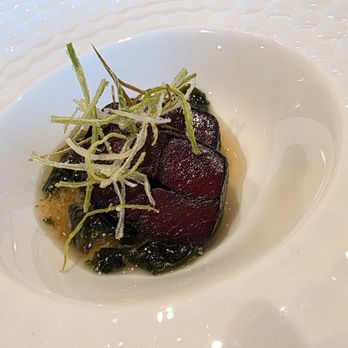 Two Nine - A dish with slices of seared tuna, garnished with herbs, served on a white textured plate. - Sushi Bars Near Me - Washington, DC, District of Columbia
