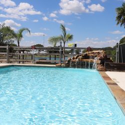 Houston West RV Park - Poolside seating with palm shade