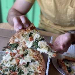 a man holding a slice of pizza a man holding a slice of pizza