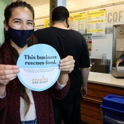 Jimbo's employee places food rescue cling in store front window