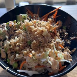 Poke Bowl - A black bowl filled with a vegetable salad including shredded cabbage, carrots, and edamame, topped with crispy fried onions and drizzled with dressing.